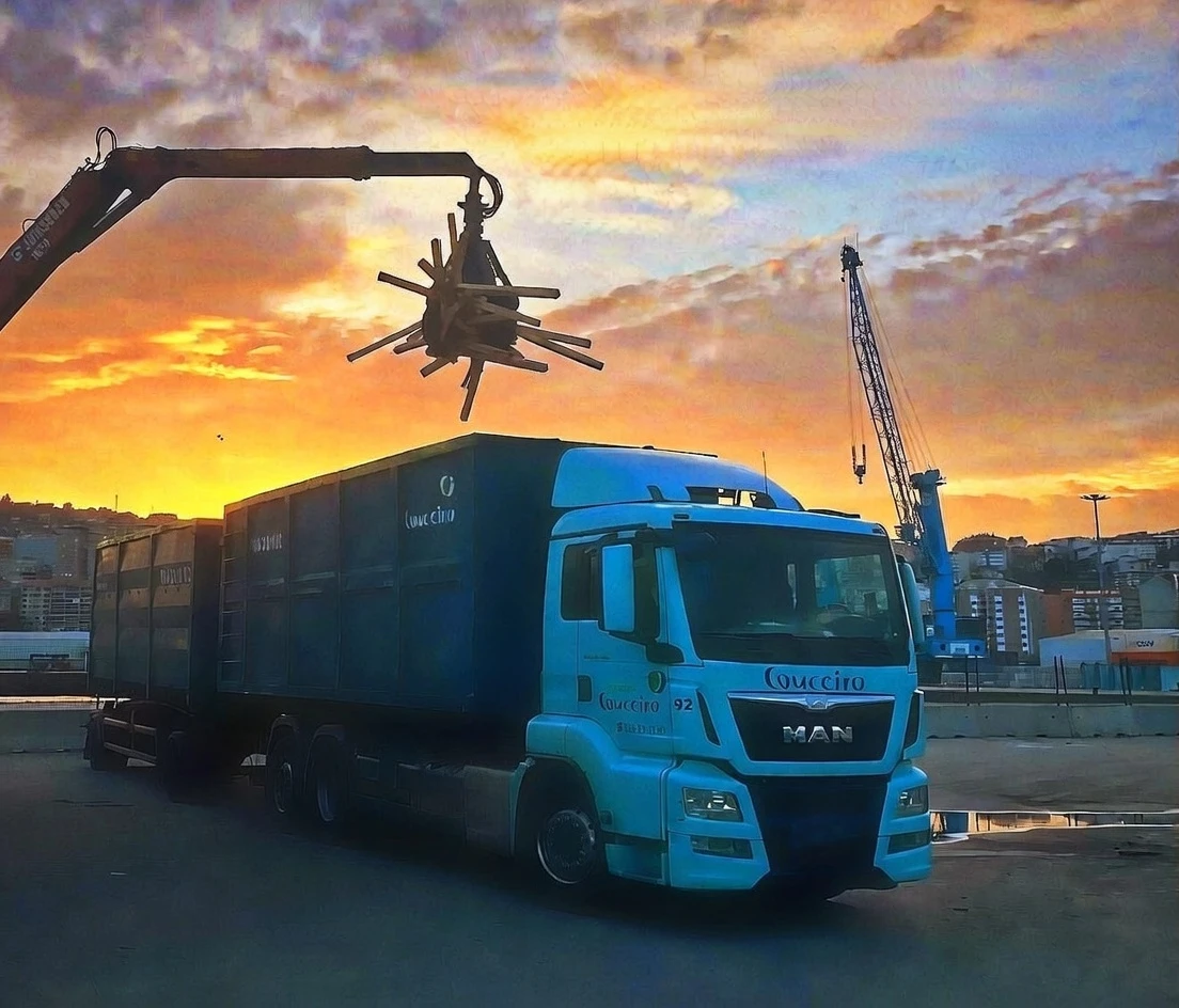 Camión grúa de Grupo Couceiro cargando residuos de madera al atardecer